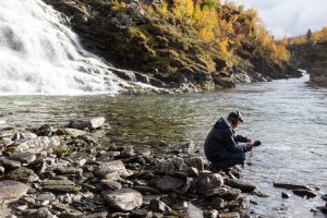 A soundscape ecologist takes a recording by a river.