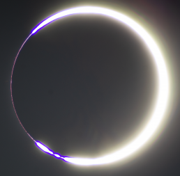 The Moon has moved in front of the Sun. The Sun’s light is reduced to a thin, bright crescent shining around the Moon’s edge. A phenomenon called Baily’s Beads is also present. Baily’s Beads look like a few glowing pearls at the ends of the crescent.