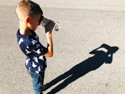 Child using a special projector to view the eclipse by looking at the ground through a projector to utilize the shadow on the ground to view the eclipse safely.