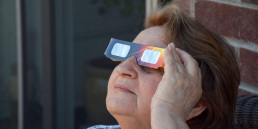 A crowd uses handheld solar viewers and solar eclipse glasses to safely view a solar eclipse.
