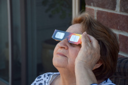A crowd uses handheld solar viewers and solar eclipse glasses to safely view a solar eclipse.