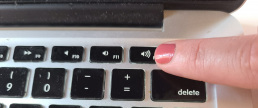 Finger pressing the volume up button on a laptop keyboard