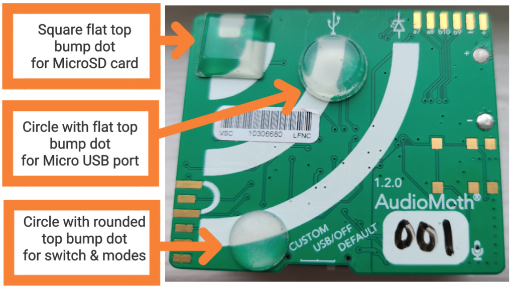 The top of an AudioMoth device, which looks like a circuit board. There are three distinct bump dots on the board, each marked with a specific function. A square flat top bump dot is positioned at the top left, indicating the location for inserting a MicroSD card. A circle with a flat top bump dot is located below the square dot, identifying the Micro USB port. A circle with a rounded top bump dot is situated towards the bottom right, denoting the switch and modes, labeled as "CUSTOM," "USB/OFF," and "DEFAULT." Each bump dot is highlighted with an orange arrow and label for clear identification. The board also contains various circuitry and a barcode labeled "VSC 10306580 LFNC" on the left side