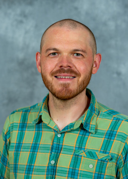 white man wearing a button down shirt and smiling directly at the camera